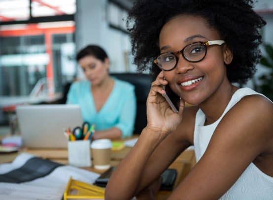 Female graphic designer in glasses smiling while talking on phone